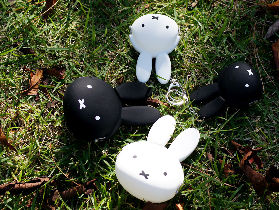 米飛兔吊飾跟口金包躺在草地上休息，光線從遠處撒過來。